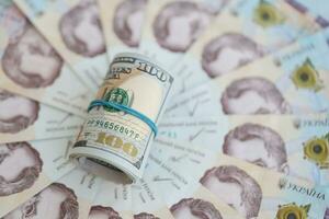 knippa av hundra oss dollar räkningar lögner på många sedlar av ukrainska hryvnias. ekonomisk standard, kris och devalvering av ukrainska nationell valuta foto
