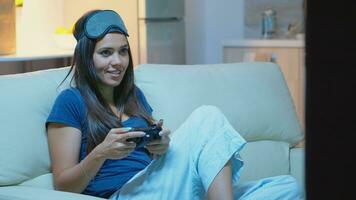 gamer använder sig av joystick spelar video spel på trösta Sammanträde på soffa i levande rum. upphetsad fast besluten kvinna använder sig av kontrollant gamepad knappsats playstation gaming och har roligt vinnande elektronisk spel foto