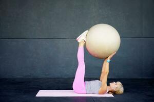 flexibel kvinna håller på med pilates övning med kondition boll i Gym på matta foto