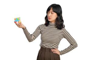 asiatisk kvinna innehav en pussel kub stående på vit bakgrund. lösning kubisk problem, problem lösning och framställning strategisk rör sig begrepp foto