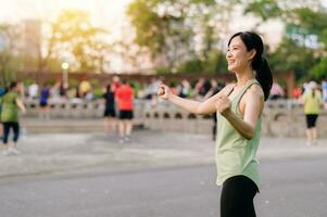 kvinna joggare. passa ung asiatisk kvinna med grön sportkläder aerobics dansa övning i parkera och njuter en friska utomhus. kondition löpare flicka i offentlig parkera. wellness varelse begrepp foto