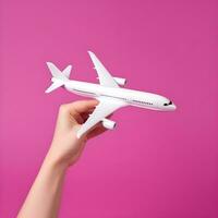 ai genererad hand innehav vit modell flygplan på rosa bakgrund foto