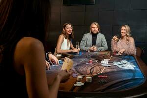 fokuserade man och två leende damer spelar poker på gaming tabell i kasino foto