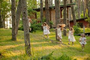 grupp av Lycklig preteen flickor löpning bland träd på grön gräsmatta i Land egendom foto
