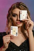 brunhårig kvinna i svart skinande klänning som visar två spelar kort, Framställ på färgrik bakgrund. hasardspel underhållning, poker, kasino. närbild. foto