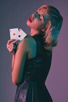 blond flicka i svart eleganta klänning som visar två spelar kort, Framställ mot färgrik bakgrund. hasardspel underhållning, poker, kasino. närbild. foto