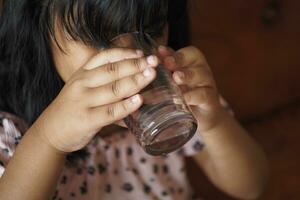 barn hand innehav en glas av vatten foto