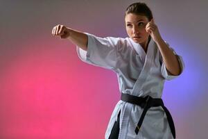 atletisk kvinna i traditionell kimono är praktiserande karate i studio. foto