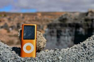 ett orange musik spelare Sammanträde på topp av en klippig klippa foto