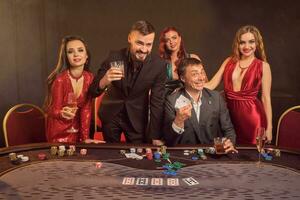 grupp av en ung rik vänner är spelar poker på en kasino. foto
