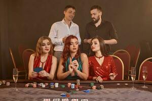 grupp av en ung rik vänner är spelar poker på en kasino. foto