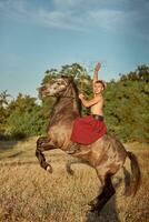 stilig man cowboy ridning på en häst - bakgrund av himmel och träd foto