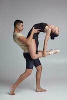 två atletisk modern balett dansare är Framställ mot en grå studio bakgrund. foto