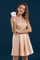 ung skön kvinna innehav de vinnande kombination av poker kort på mörk blå bakgrund. två ess foto