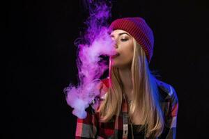 vaping flicka. ung hipster kvinna vape e-cig på studio på svart bakgrund. hiphop stil. stänga upp. foto