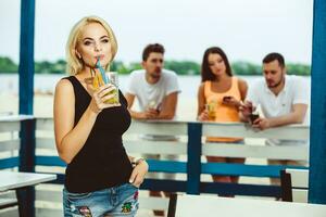 blond flicka på en sommar terrass i en bar drycker cocktail foto