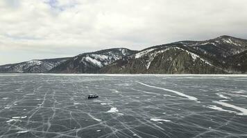 vinter- baikal sjö med turister på is har roligt. klämma. antenn se av människor utforska vild natur av de frysta sjö på molnig himmel bakgrund. foto