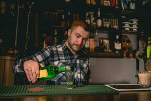 bartender häller grön banan likör in i skott glas medan framställning cocktail grön mexikansk foto