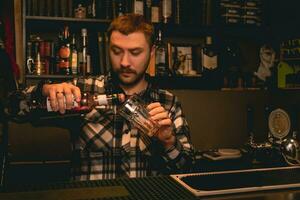 bartender häller granatäpple sirap från flaska in i grogg glas foto