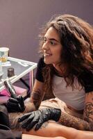 leende flicka tatuerare talande vänlig till klient medan få tatuering foto