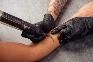 händer av tatuering konstnär tatuering ord estetisk på klient underarm foto