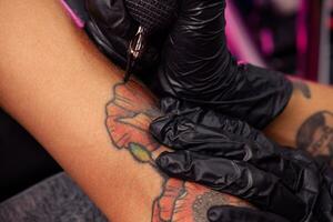 skapande av färgrik vallmo tatuering på kvinna ärm använder sig av tatuering maskin foto