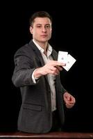 ung caucasian man bär kostym innehav två ess i hans hand på svart bakgrund. hasardspel begrepp. kasino foto