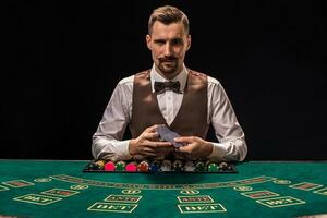 porträtt av en croupier är innehav spelar kort, hasardspel pommes frites på tabell. svart bakgrund foto