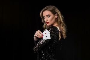 ung kvinna innehav spelar kort mot en svart bakgrund foto