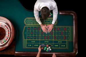 man croupier och kvinna spelar roulett på de tabell i de kasino. topp se på en roulett grön tabell med en tejp mäta. foto