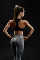 skott av en stark kvinna med muskulös buk i sportkläder. kondition kvinna modell Framställ på svart bakgrund. foto