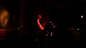 de silhuett av en kvinna dansare innehav Smycken i de mörk av natt är belyst förbi de ljus av en brinnande brand foto