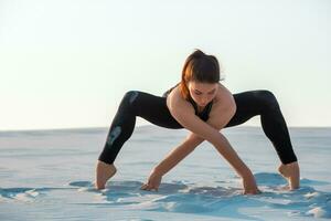 kondition yoga kvinna stretching på sand. passa kvinna idrottare håller på med yoga utgör. foto