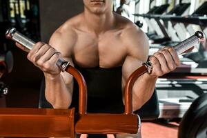 muskulös man håller på med övningar i de Gym. del av de kropp. naken manlig torso foto