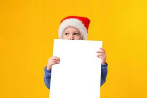 söt liten flicka i santa claus hatt med en vit tom papper ark. jul, jul, ny år, vinter, människor, annons, försäljning begrepp. foto