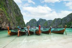 trä- lång svans båtar förankrade på maya bukt med kalksten berg räckvidd och turkos hav i phi phi ö på krabi, thailand foto