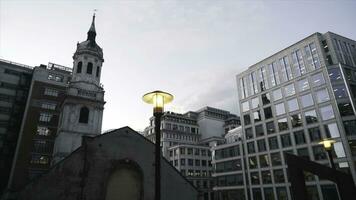 närbild av gul gata lampor i de Centrum av London nära de modern glas skyskrapor mot de blå kväll himmel. handling. kväll stad landskap foto