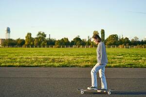 hobbies och livsstil. ung kvinna ridning skateboard. skater flicka njuter kryssning på longboard på solig dag utomhus foto