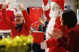 Lycklig person vinnande ge bort tävling i handla köpcenter, känsla upphetsad handla om kampanjer och fri kläder som lotta ut pris. santa claus cosplay tillkännager senior kvinna vinnare, teckning namn. foto