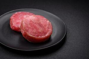 runda form biffar av rå saftig tonfisk med salt och kryddor foto