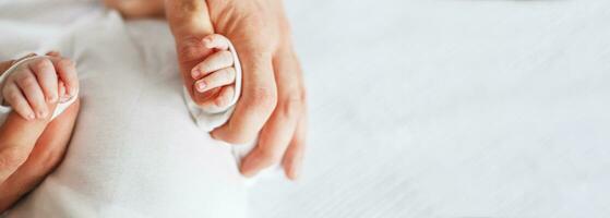 stänga upp Foto av far innehav nyfödd bebis hand.