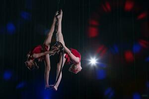 cirkus skådespelerska akrobat prestanda. två flickor prestera akrobatisk element i de luft ringa. foto