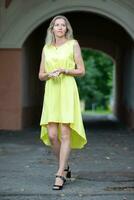äldre smal kvinna blond i full tillväxt i en sommar gul klänning. foto