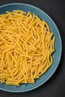 rå hela spannmål vete pasta med salt och kryddor i en keramisk tallrik foto