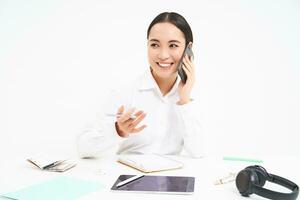 bild av kontor anställd, asiatisk kvinna i kontor samtal på mobil telefon, diskuterar arbete på mobiltelefon, vit bakgrund foto