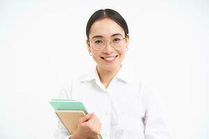 asiatisk kvinna, lärare med anteckningsböcker, leende och ser självsäker, isolerat på vit bakgrund foto