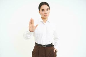 sluta. sträng och allvarlig lady chef, asiatisk kvinna visar utökad hand, avslag, förbjuda gest, vit bakgrund foto