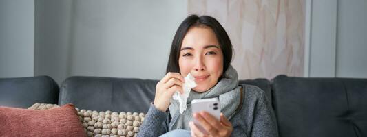 porträtt av sjuk kvinna kontaktar henne gp via mobil telefon medan fångst kall, Sammanträde med influensa på Hem, använder sig av smartphone foto