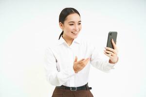 porträtt av företags- kvinna, chef video chatt på mobil telefon, utseende på smartphone och leder en möte uppkopplad via smartphone app, vit bakgrund foto