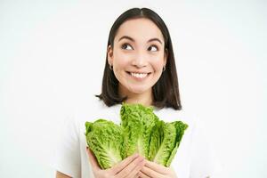 vegetarian näring. leende Lycklig ung kvinna utseende på henne själv vuxen kål, äter sallad, vit bakgrund foto